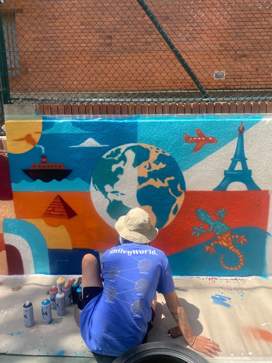 Matt painting a travel-themed mural with a globe and landmarks